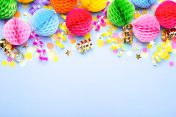 Birthday party background on violet. Top view. Border made of colorful serpentine, balls and confetti.