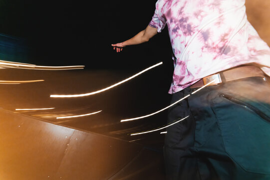 A large plan is a piece of athlete on a skateboard to ride quickly at night on a skateboard in a skatepark. A compilation of dashing youth nightlife in the city. Long exposure of lubricant in motion - Powered by Adobe