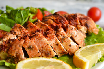 Grilled chicken breast salad with spinach and tomatoes. Healthy eating Fried chicken breast, lemon, cherry tomatoes, spinach and lettuce. Closeup. close up.