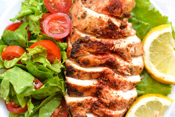 Grilled chicken breast salad with spinach and tomatoes. Healthy eating Fried chicken breast, lemon, cherry tomatoes, spinach and lettuce. Closeup. close up.