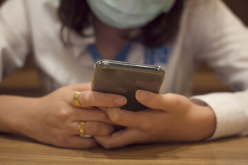 Young woman cover face with mask holding, using mobile smart phone, close up.