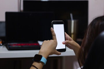 young woman working from home using smart phone and laptop computer, girl hands holding white screen smart phone working at home using technology,