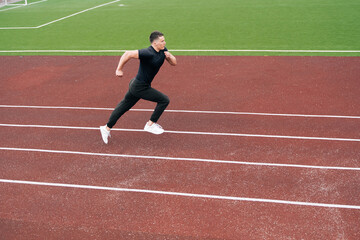 The sprinter started accelerating while running. A man is engaged in athletics on a red treadmill. Sports ground with a special coating for the athlete