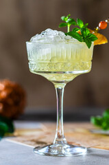 Cold freshly squeezed pineapple juice with crushed ice and mint on a light gray concrete background.