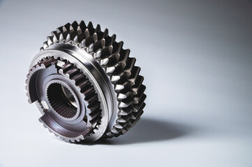 The new shiny metal gear of the switch box is fronted by a gray gradient background. The concept of new spare parts for car maintenance and repair