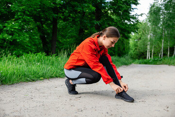 young girl tying shoelaces before running on a summer forest trail