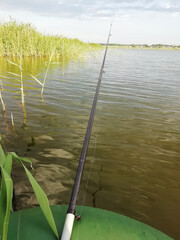 Fishing on the lake with reeds. Fishing rod from a boat.