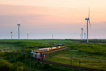 Wind farm and moving train at sunset