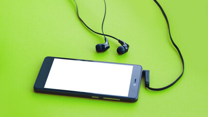 Mockup smartphone and earphones on green background.