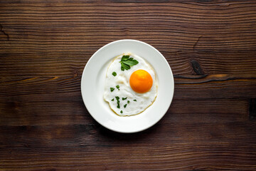 Fried eggs on plate - dark wooden kitchen table top-down