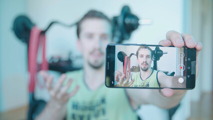 Attractive man home fitness influencer record video with smartphone