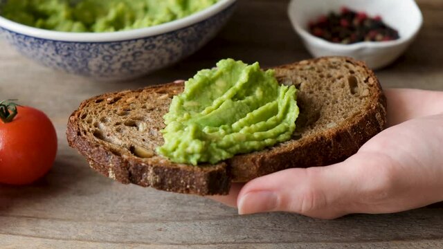 Making toast with avocado. Smear mashed avocado on whole grain rye bread