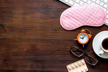 Hard exhausing work concept. Sleep mask on wooden office desk top view copyspace