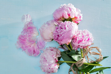 Pink peonies bouquet closeup, spring flowers for Mother's Day on ligh blue wooden background. Wedding events and other holidays.