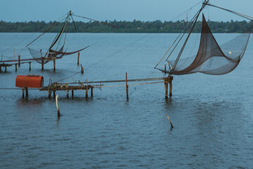 Small houses in a local village located next to Kerala's backwater on a bright sunny day and traditional Houseboat seen sailing through the picturesque backwaters of Allapuzza or Alleppey in Kerala 