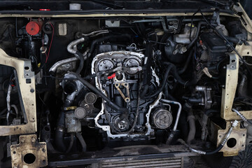Fototapeta premium disassembled front of the car in workshop prepared for repair: front end, hood and bumper removed, internal equipment, parts and spare parts visible. Auto service industry.
