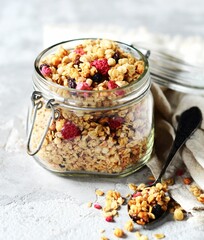 Homemade granola with berries and nuts in a bowl on a gray background
