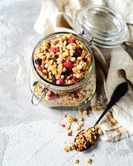 Homemade granola with berries and nuts in a bowl on a gray background