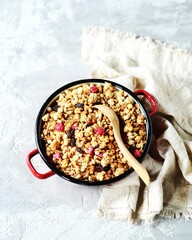 Homemade granola with berries and nuts in a bowl on a gray background