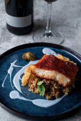 Fine dining restaurant: golden cod fillet with couscous and rice chips, garnished with unusual blue sauce