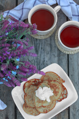 Breakfast with pancakes. Mini pancakes with flowers. Purple flowers in a pot. Pancakes with cream