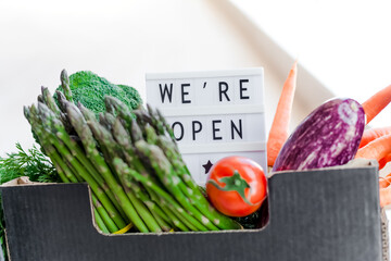 Text We're open and Fresh green and vegetables box