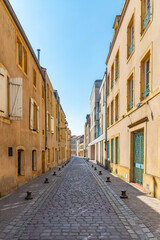 Fototapeta na wymiar Narrow cobble stone street with yellow buildings in Metz, France