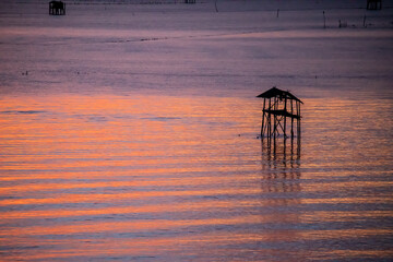 Silhouette of bamboo cottage with morning sunshine in gulf of Thailand at Bang Tabun, Phetchaburi, Thailand.