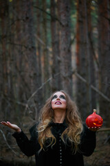 girl witch witch pumpkin on halloween in a dark pine forest