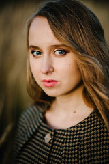 Naklejka premium Portrait of a beautiful girl in autumn on the background the nature. upper half length. Close up. looking at the camera.
