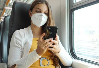 Relaxed woman with KN95 FFP2 face mask using smart phone app. Train passenger with protective mask...