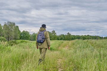 Active man in mosquito suit with backpack in hiking in a meadow. Siberia, Russia