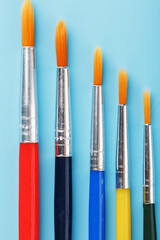 Multi-colored paint Brushes on a blue background.