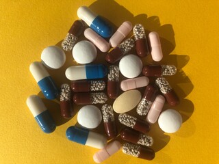 A lot of colorful pills on yellow background.