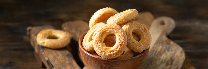 Puff pastry sprinkle with sugar in a wooden bowl on a brown wooden background. Cookies sprinkle with sugar close-up. Sweet pastries. Banner	
