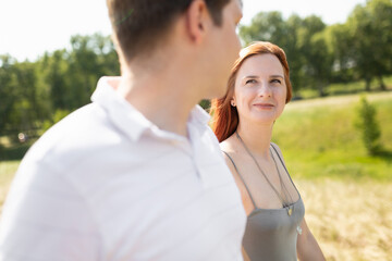 Fototapeta premium A young couple walks in nature and look at each other. The concept of a happy relationship.