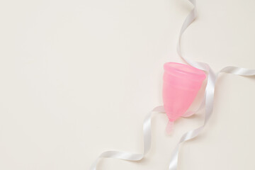 menstrual cup on light background with white ribbon