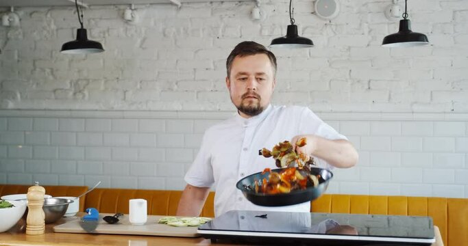 Chef tossing throws up burning with fire vegetables on frying pan. Mixing pieces