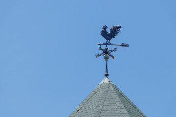 青空を背景に風見鶏と三角屋根