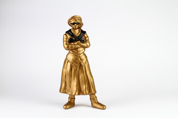 Figure of a woman in gilded plaster, with a wide skirt and shirt, sunglasses and folded arms. Central position, light background.