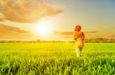 Fototapeta premium Young woman walking in field at sunset time