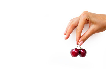 Woman with french manicure is holding 2 fresh red cherries