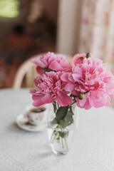 pink peonies on the table with a cup of tea