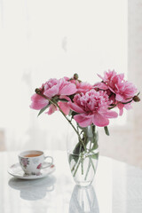 Fototapeta na wymiar pink peonies on the table with a cup of tea