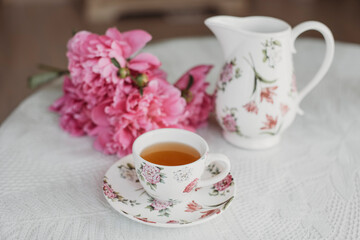 Fototapeta na wymiar pink peonies on the table with a cup of tea