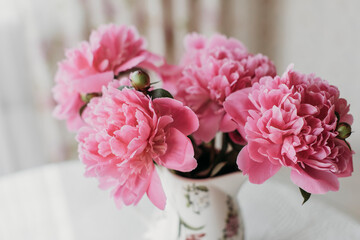 pink peonies on the table with a cup of tea