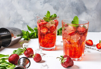 Strawberry mojito and ingredients on white wooden background