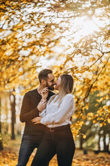 Fototapeta premium Sunny portrait of a young loving couple walking in the autumn park.