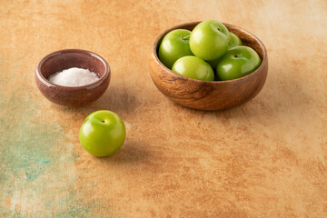 fresh ripe green plums on a table served with salt
