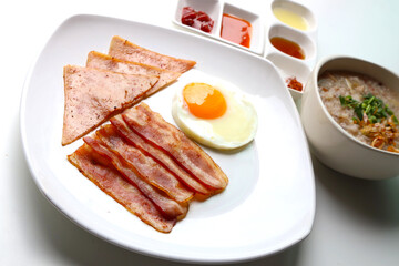 Rice Porridge, ham, bacon, fried egg, served with various sauces Put on the white table Ready to eat